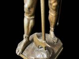 bronze statue of a man with a staff and foot on a base