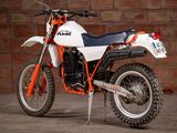 a white and orange dirt bike parked in front of a brick wall