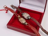 deux montres posées dans une boîte rouge sur une surface blanche