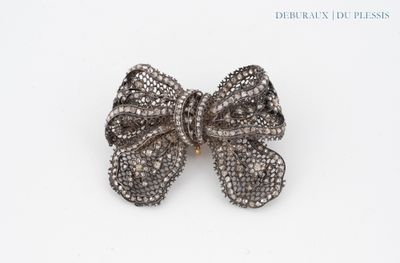 a close up of a silver bow on a white surface