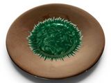 a plate with a green flower on it on a white surface