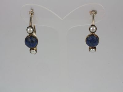 a pair of earrings with blue stones and pearls on them