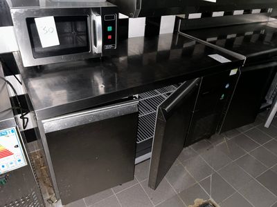 un plan de travail noir sur lequel est posé un micro-ondes