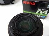 a camera lens sitting on a table next to a box of pentax