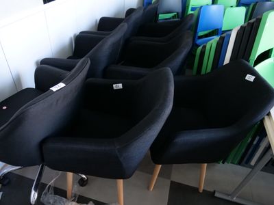 several black chairs are lined up in a row on a checkered floor
