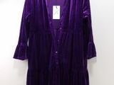 une robe violette suspendue à un cintre sur un mur blanc