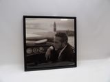 photographie en noir et blanc d'un homme assis dans une voiture avec une planche de surf