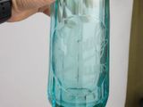 a person holding a blue glass bottle with a toothbrush in it