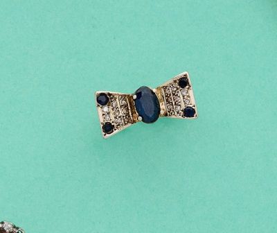 deux bijoux posés sur une surface verte, sur fond bleu