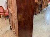 a tall wooden cabinet in the middle of a room