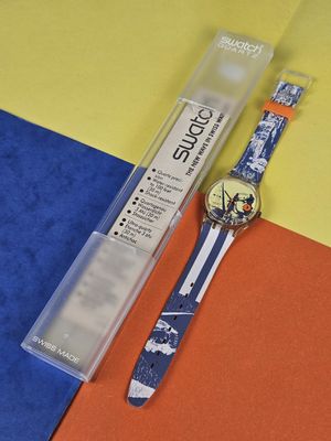 a watch and a pen sitting on a colorful surface