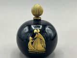 une image représentant un flacon de parfum noir et doré posé sur une surface blanche