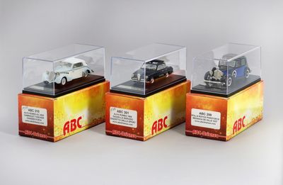 trois voitures miniatures dans une vitrine posée sur une table