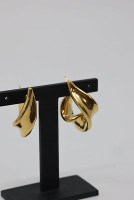 a close up of a pair of gold earrings on a black stand