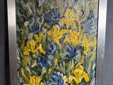 tableau représentant des fleurs jaunes et bleues dans un cadre argenté sur fond noir