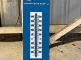 a blue and white thermometer sitting on the ground