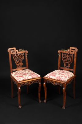 a pair of antique chairs with floral upholstered cushions