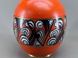 un vase orange orné de motifs noirs et blancs