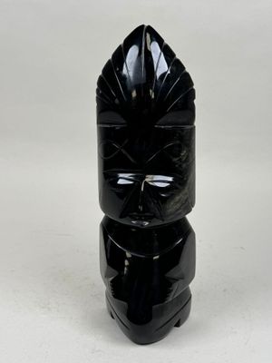 un vase noir orné d'un visage sur un fond blanc
