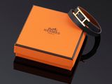 un bracelet noir et orange avec une boucle dorée sur un fond noir