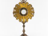 an ornate gold sunburst with a crown on top of it
