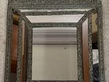 un miroir en argent richement décoré accroché au mur d'une pièce