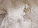 a white wedding dress on a bed next to a pillow