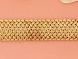 un bracelet au crochet et une paire de ciseaux posés sur un fond rose