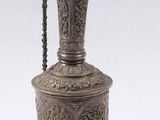 un vieux vase en argent dont le col est orné d'une chaîne