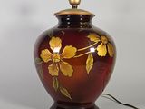 un vase rouge orné de fleurs jaunes, posé sur une table