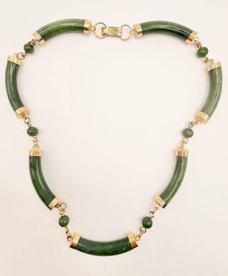 a necklace with green beads and gold accents on a white background
