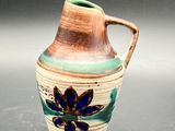 a small vase with a flower on it on a table