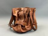 une image représentant un sac à main en cuir marron sur fond gris