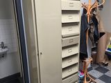 a tall metal cabinet with a bunch of clothes hanging on it