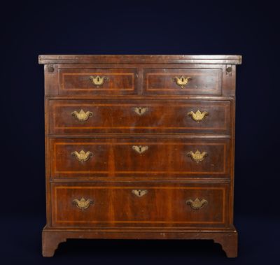 a walnut chest of drawers with brass handles
