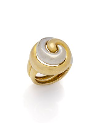 gros plan d'une bague en or et en argent sur une surface blanche