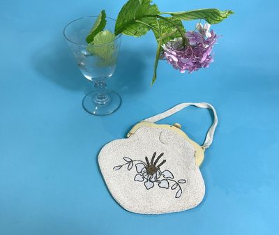 a small bag with a spider on it next to a vase