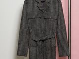 un manteau accroché à un porte-manteau devant un mur rose