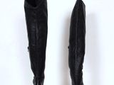 pair of black leather high heeled boots on a white pedestal
