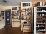 bottles of wine and wine glasses are on shelves in a wine shop