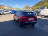 a red car is parked in a parking lot with other cars in the background