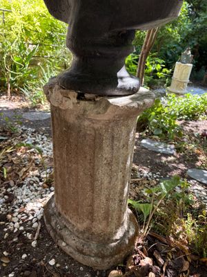 a statue of a man sitting on top of a stone pedestal