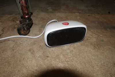 une petite enceinte blanche posée par terre à côté d'un tuyau
