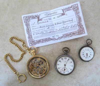 trois montres de poche posées à côté d'un certificat sur une table