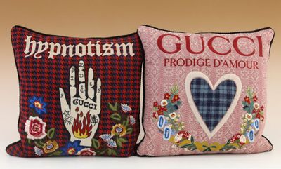 two pillows with embroidered designs on them are sitting on a table
