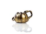 a gold teapot with a handle on a white surface