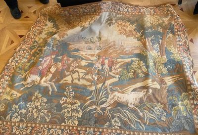 a very large tapestry on the floor with people standing around it