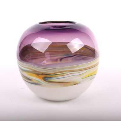un vase en verre violet avec un socle blanc, posé sur une table