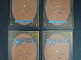 four magic the gathering trading cards are sitting on a table