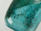 a green vase with writing on it sitting on a table